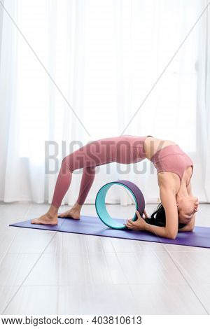 Young Woman Do Wheel Yoga In A Bed Room