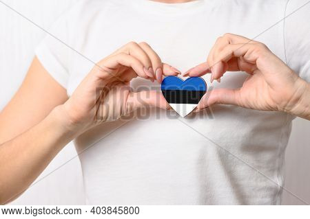 Love Estonia. The Girl Holds A Heart In The Form Of The Flag Of Estonia On Her Chest. Estonian Conce