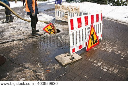 Road Works Sign. The Municipal Service Removes The Blockage In The Sewer Hatch. Severe Winter Frosts