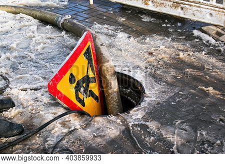 Road Works Sign. The Municipal Service Removes The Blockage In The Sewer Hatch. Severe Winter Frosts