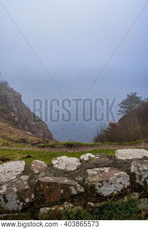 A View Over The Ocean From A Steep Hill A Misty Day. Picture From Kullen Nature Reserve, Scania Coun