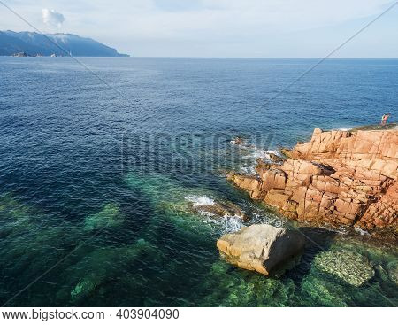 Red Rocks Called Rocce Rosse At Mediterranean Sea Coastline In Arbatax With Two Boys Fishing. Tortol