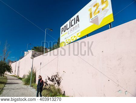 Lisbon, Portugal - Feb 10, 2018: Lonely Woman Near Tall Stone Fence With Policia Lisboa Banner Celeb