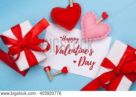Valentines day greeting card. Gift boxes and heart shaped decor over blue background. Top view flat lay
