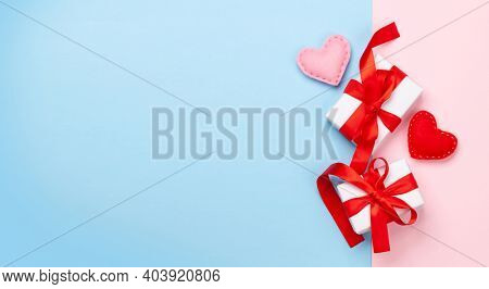Valentines day greeting card template. Gift boxes and heart shaped decor over blue and pink background. Top view flat lay with copy space