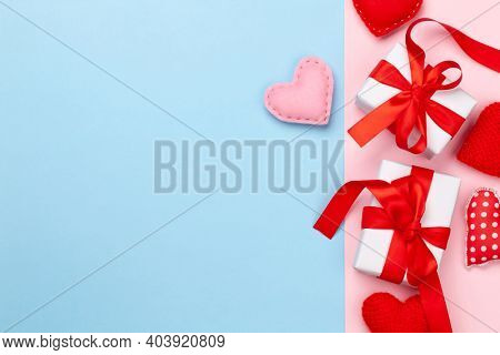 Valentines day greeting card template. Gift boxes and heart shaped decor over blue and pink background. Top view flat lay with copy space
