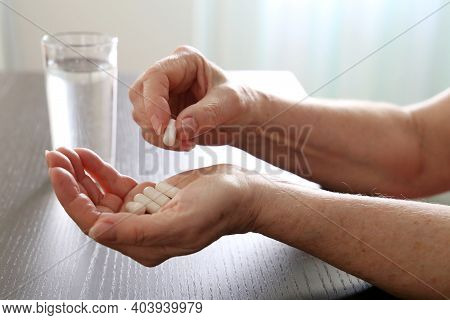 Elderly Woman With Pills In Wrinkled Hands. Medication In Capsules, Taking Sedatives Or Vitamins