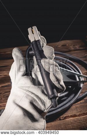 The Welder In White Welding Leather Gloves Holds A Wire With An Electrode Holder In His Hand. Studio