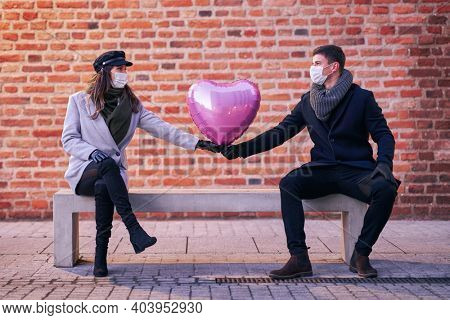 Happy couple celebrating Valentines Day in masks during covid-19 pandemic