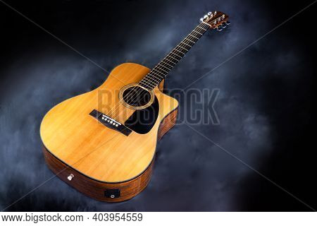 Acoustic Classical Yellow Six-string Guitar With Black Pickguard In Smoke On Black Isolated Backgrou