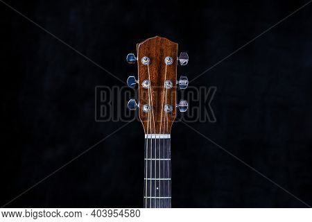 Acoustic Guitar Head With Chrome Tuning Pegs And Fretboard On Isolated Black Background