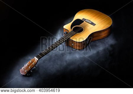 Acoustic Six-string Guitar Of Classic Yellow Color On Isolated Black Background Surrounded By Fog