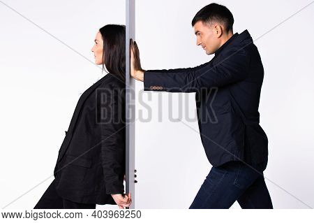 A Self-confident Business Woman Is Leaning Her Back Against The Wall And The Man Is Pushing An Impro