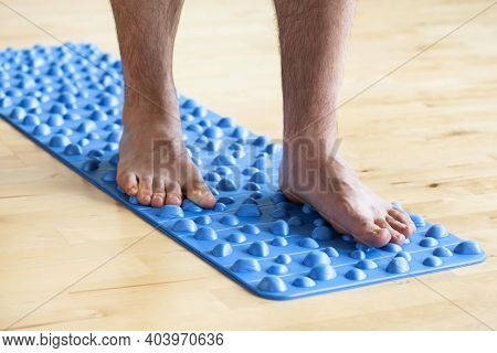 man doing flatfoot correction gymnastic exercise walking on massage mat at home