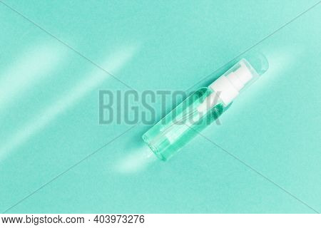 Small Bottle With Transparent Cosmetic Product, Gel Or Crem On Mint Colored Background. Flack With M