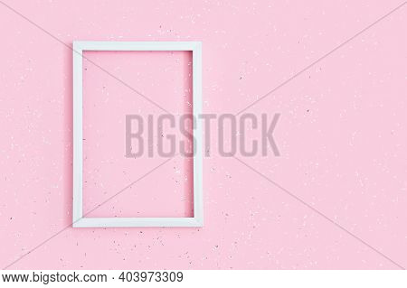 Holiday Concept. Square White Frame On Pink Paper Background Covered With Sequins With Copy Space. B