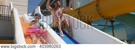 Man And His Daughter Ride Slide In Water Park. Family Weekend In Aquazone Pool Concept.