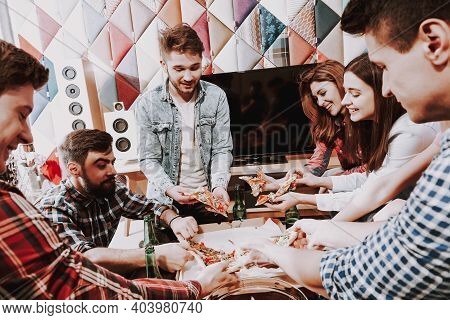 Group Of Friends Gathering Around Coffee Table At Home. Friends Gathered At The Table And Drinking B