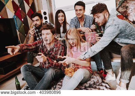 Group Of Friends Gathering Around Coffee Table At Home. Friends Gathered At The Table And Drinking B