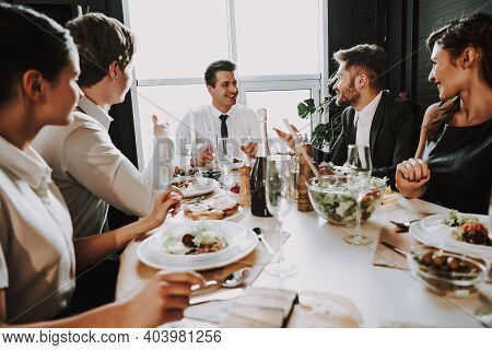 Group Of Friends Gathering Around Coffee Table At Home. Friends Gathered At The Table And Drinking B
