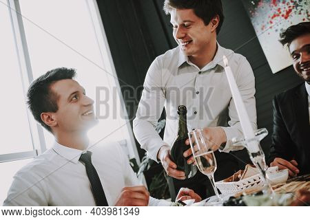 Group Of Friends Gathering Around Coffee Table At Home. Friends Gathered At The Table And Drinking B