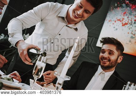 Group Of Friends Gathering Around Coffee Table At Home. Friends Gathered At The Table And Drinking B