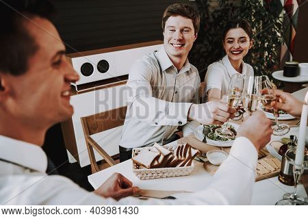 Group Of Friends Gathering Around Coffee Table At Home. Friends Gathered At The Table And Drinking B