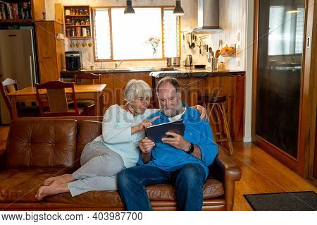 Happy Active Senior Man And Woman Video Calling Family Using Digital Tablet. Couple Enjoying Togethe