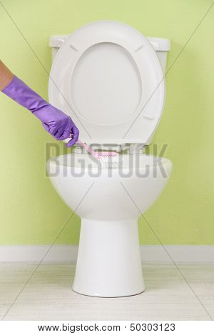 Woman hand with brush cleaning a toilet bowl in a bathroom
