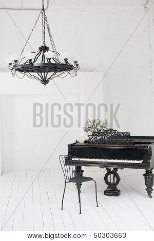 A beautiful chandelier and a piano in the room with white floors and walls