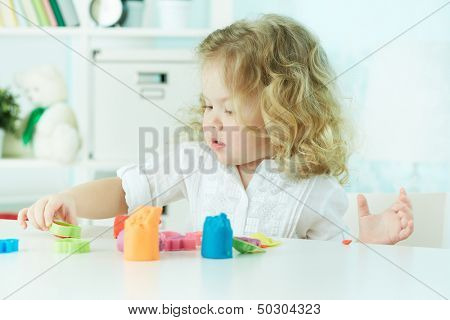 Little girl modeling with clay at kindergarten