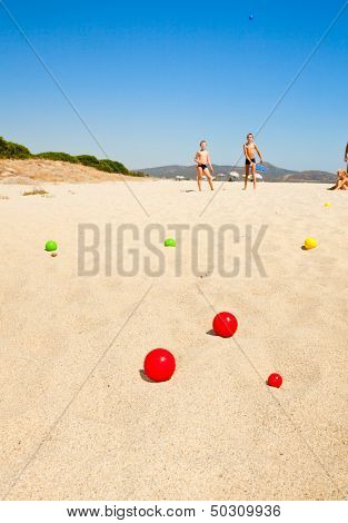 Boys playing petanque on a beach, focus on balls