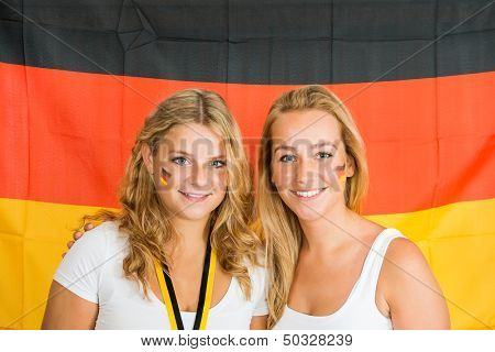 Portrait of beautiful young sportswomen standing against German flag
