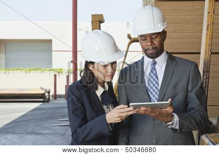 Multiethnic contractors using tablet PC at timber yard