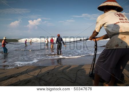 PADANG - AUGUST 25: Fishermen work as a team pull in the fishing nets from the sea in Padang, West Sumatera, Indonesia on August 25, 2013. Resources from the sea is a major revenue earner.  