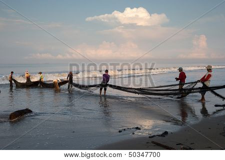 PADANG - AUGUST 25: Fishermen work as a team pull in the fishing nets from the sea in Padang, West Sumatera, Indonesia on August 25, 2013. Resources from the sea is a major revenue earner.  