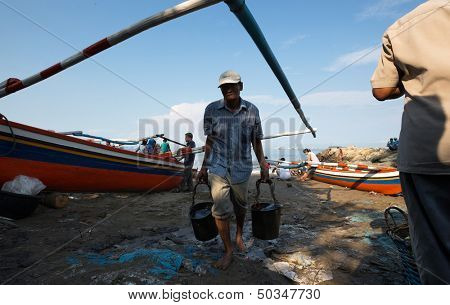 PADANG - AUGUST 25: A fisherman returns from his boat with two pails of fish for sale at an outdoor village market in Padang, West Sumatera, Indonesia on August 25, 2013. 