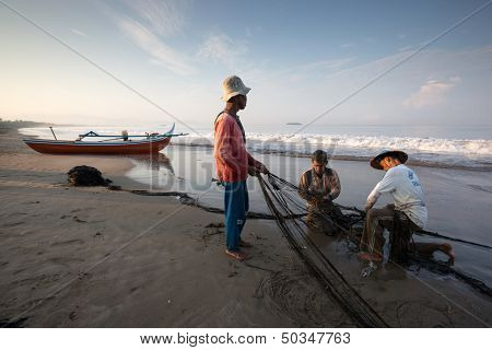 PADANG - AUGUST 25: Fishermen work as a team harvest the fish caught in the fishing nets in Padang, West Sumatera, Indonesia on August 25, 2013. Resources from the sea is a major revenue earner. 