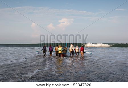 PADANG - AUGUST 25: Fishermen work as a team launch the boat to sea in Padang, West Sumatera, Indonesia on August 25, 2013. Resources from the sea is a major revenue earner. 