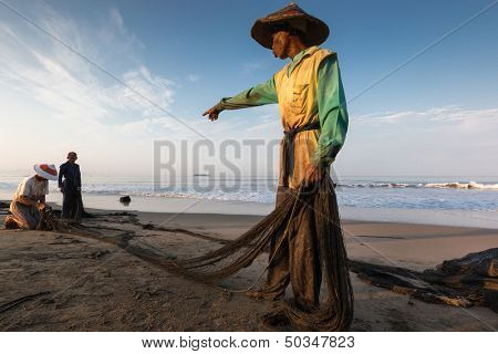 PADANG - AUGUST 25: A fisherman commanders his mates mending the nets for the next cast at sea in Padang, Sumatera, Indonesia on August 25, 2013. Resources from the sea is a major revenue earner.  