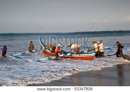 PADANG - AUGUST 25: Fishermen work as a team launch the boat to sea in Padang, West Sumatera, Indonesia on August 25, 2013. Resources from the sea is a major revenue earner.  