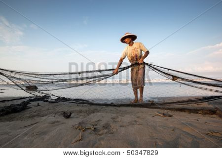 PADANG - AUGUST 25: A fisherman folds up the fishing nets in preparation for the next cast in Padang, West Sumatera, Indonesia on August 25, 2013. Resources from the sea is a major revenue earner.  
