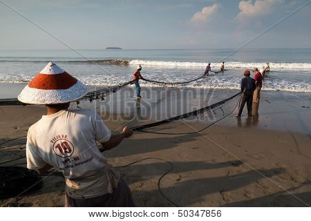 PADANG - AUGUST 25: Fishermen work as a team pull in the fishing nets from the sea in Padang, West Sumatera, Indonesia on August 25, 2013. Resources from the sea is a major revenue earner.  