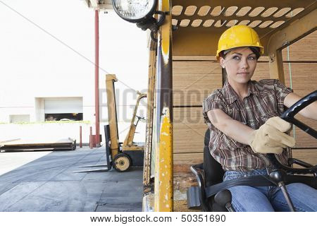 Female industrial worker driving forklift truck