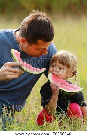 Father And Young Daughter Eat Watermelon In Nature