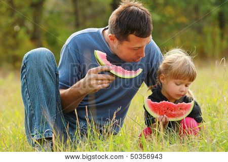 Father And Young Daughter Eat Watermelon In Nature