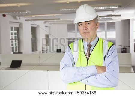 Portrait of middle-aged man in reflector vest and hard hat at office