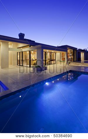 Rear view of luxury villa at night time with swimming pool