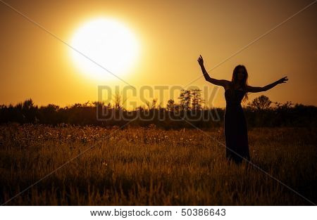 Silhouette Of Dancing Young Girl In Dress Against The Sunset Sky