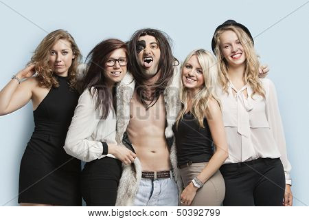 Portrait of playboy and happy women standing together against light blue background